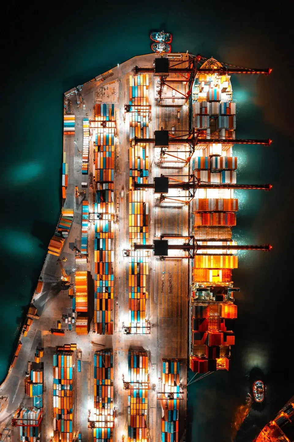 Aerial view of a container terminal at night, stacks of containers under floodlights